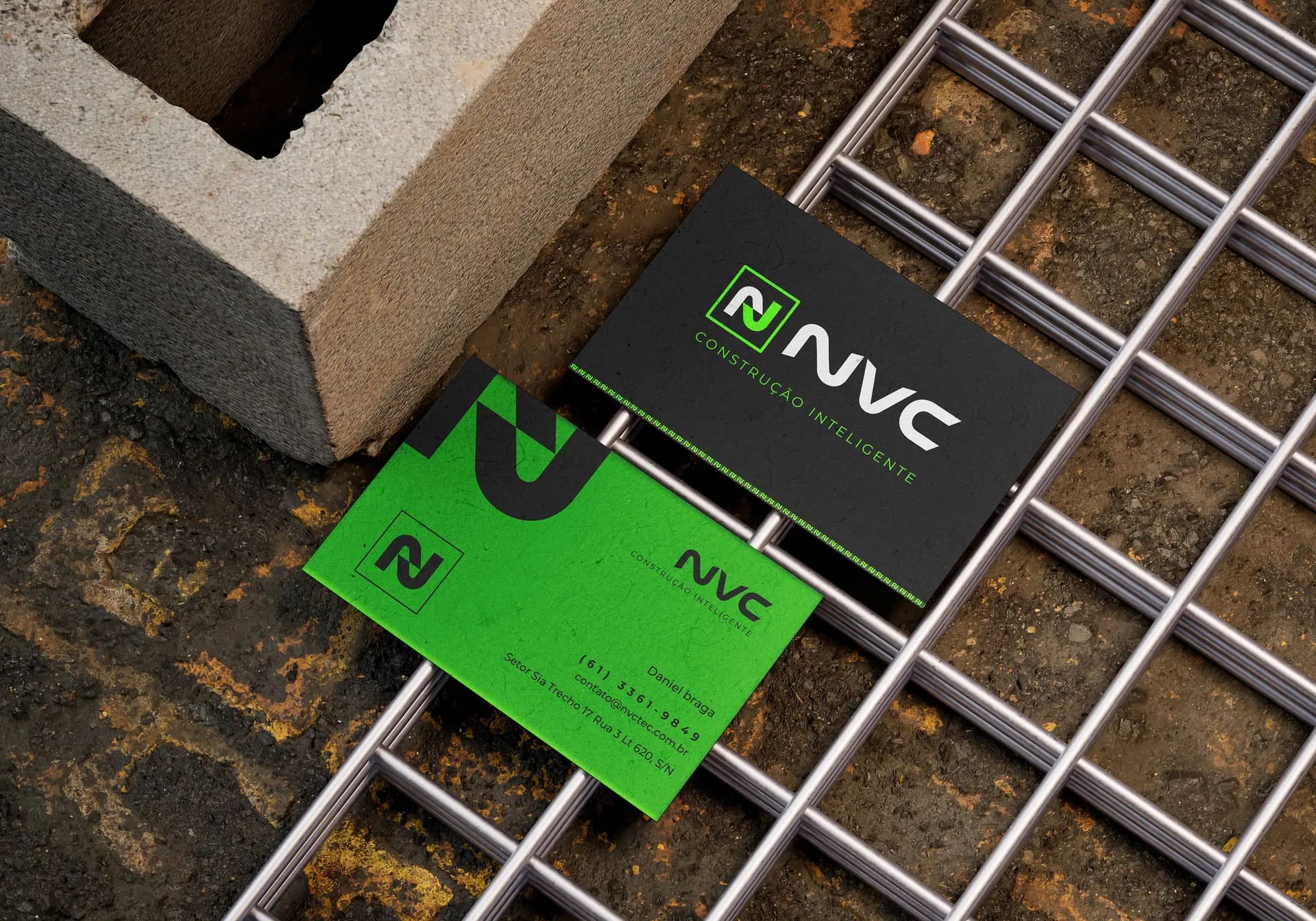 Cartões de visita NVC Tech em verde e preto, apoiados sobre malha de aço e bloco de concreto