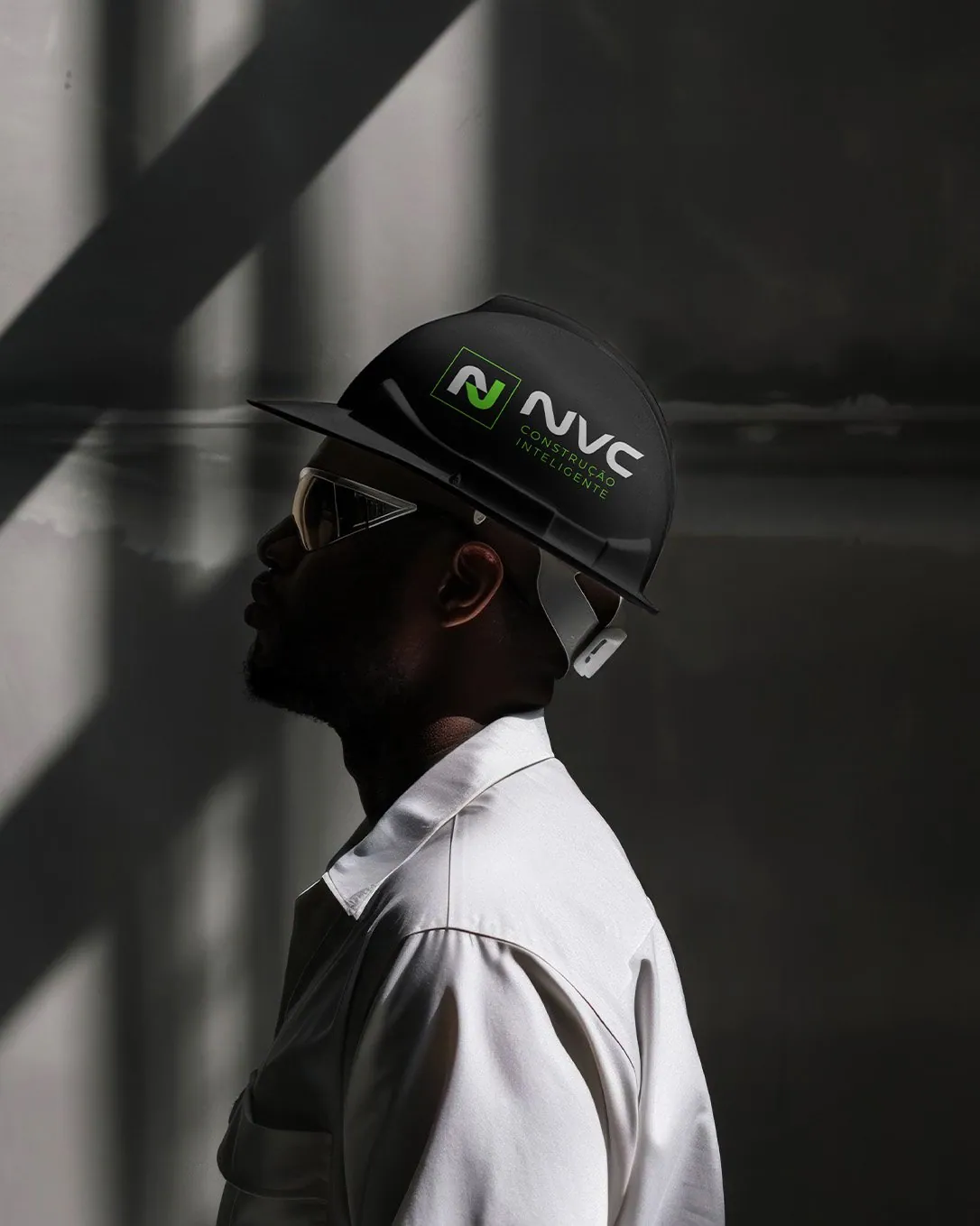 Profissional de perfil usando capacete preto com a marca NVC Tech, camisa branca