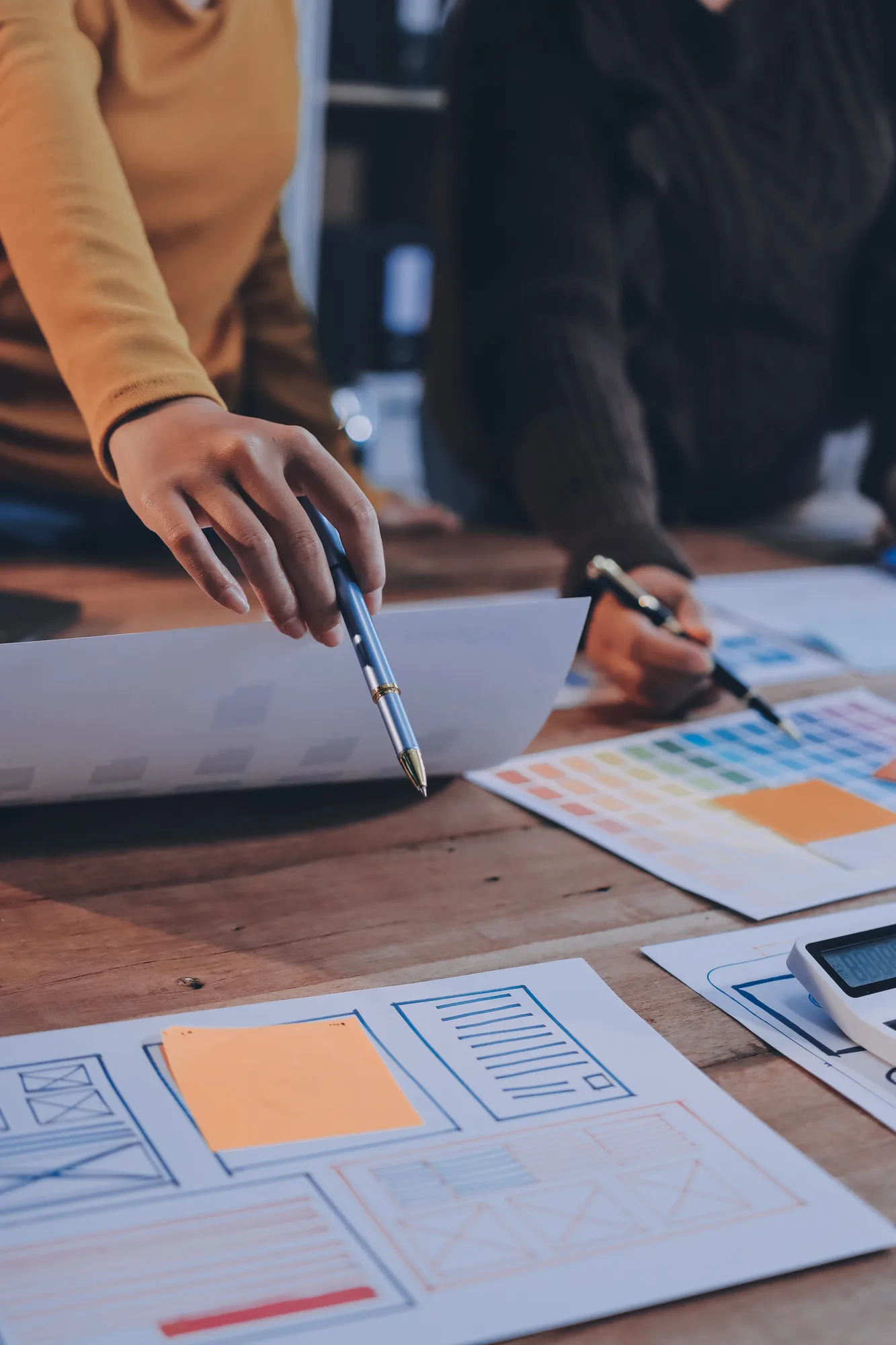 Mesa de trabalho com wireframes e paleta de cores impressa